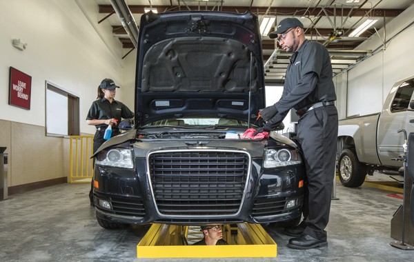 two Jiffy Lube mechanics cleaning the hood and exterior of a vehicle