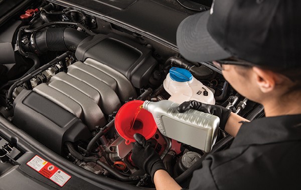 Jiffy Lube car expert pouring oil into a car's engine