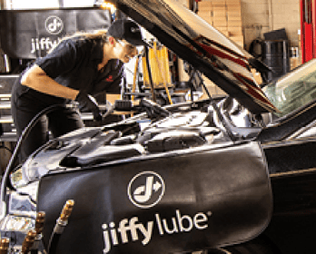 a woman Jiffy Lube car expert checking a car's engine for repair and maintenance