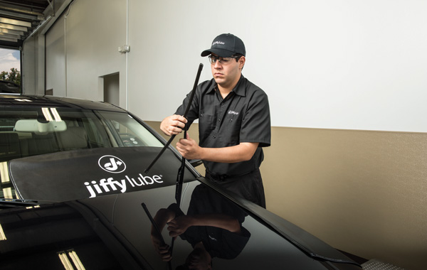 Jiffy Lube car expert wiping a wiper blades.