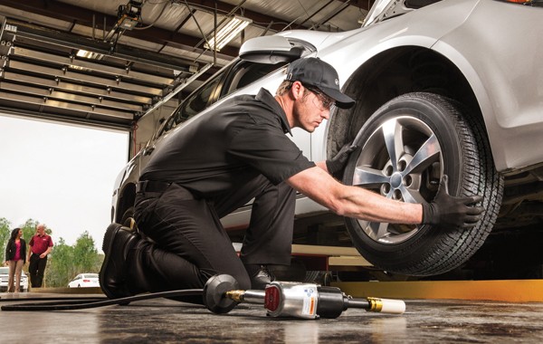 Jiffy Lube car mechanics switching a tire from one spot to another spot. This is called tire rotation.