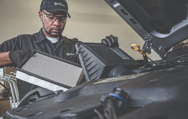 Jiffy Lube car mechanic replacing an old filter with a new car filter