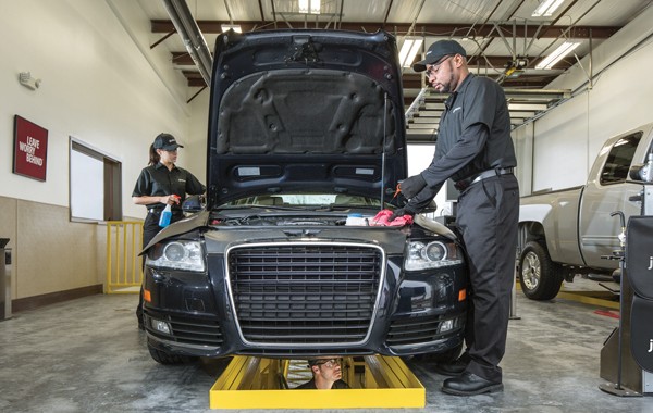 two Jiffy Lube car experts cleaning the exterior of a car