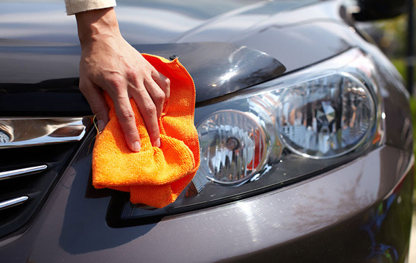 Hand with microfiber cloth cleaning car.