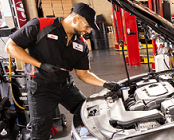 Jiffy Lube car expert fixing the engine of a car while smiling